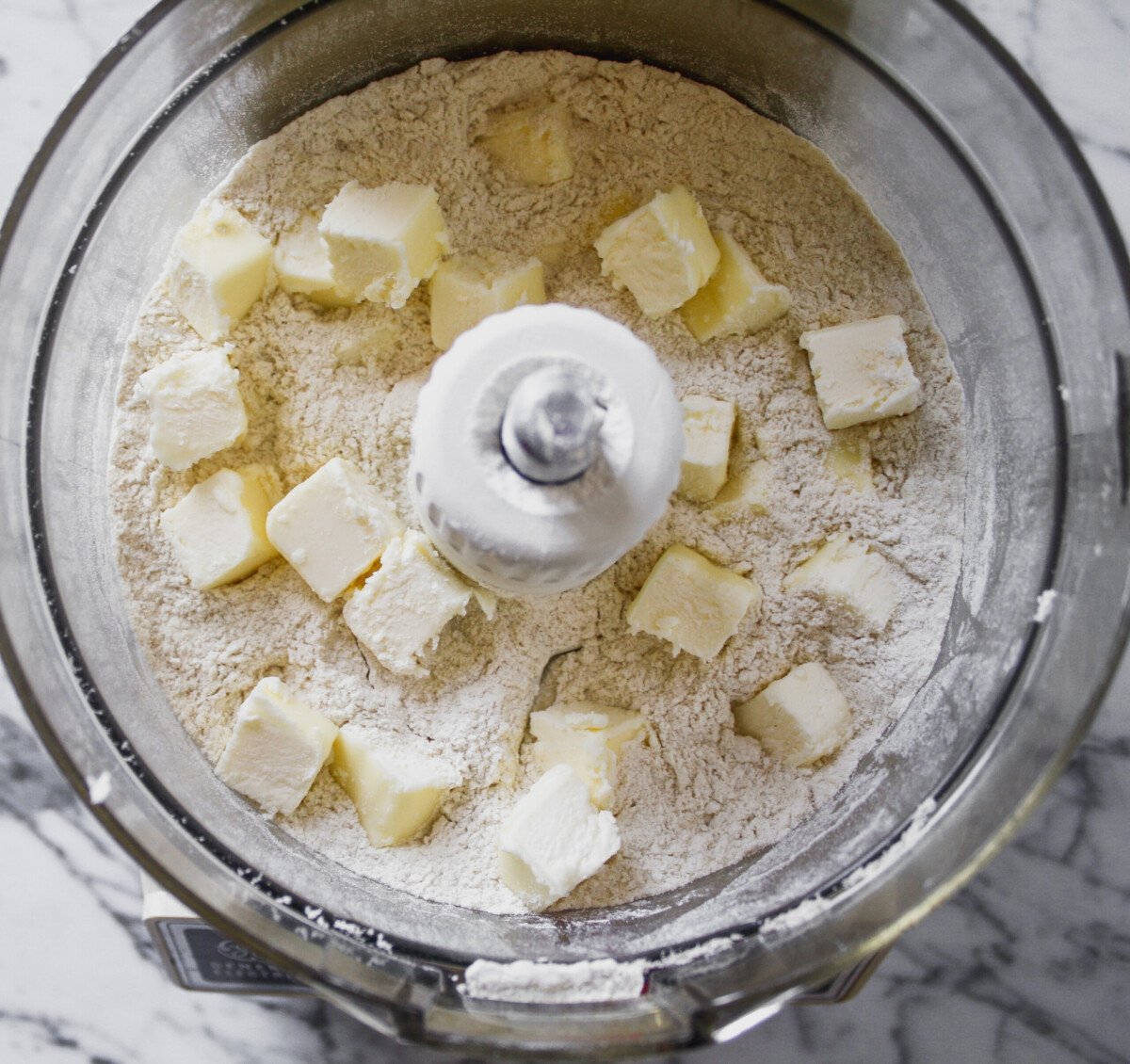 Butter cubes on top of flour in a food processor.