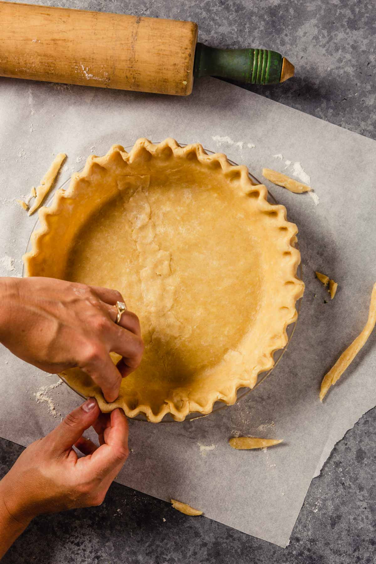 pie dough being crimped in a pie plate