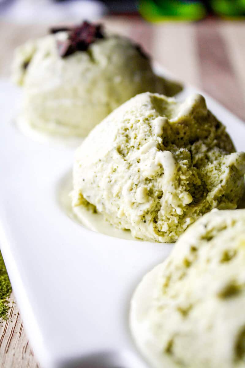 Photograph of a scoop of green tea ice cream on a white plate. 