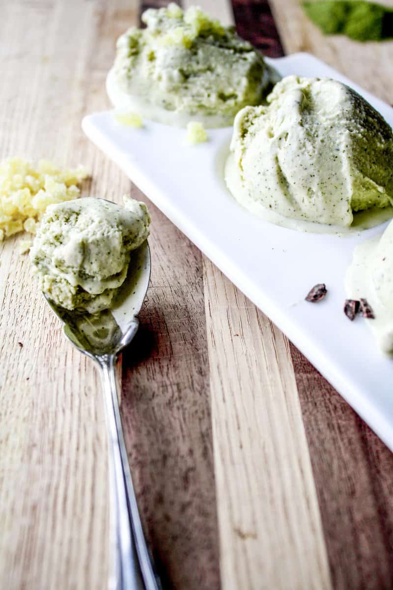 Photograph of green tea ice cream on a spoon set on a wood table