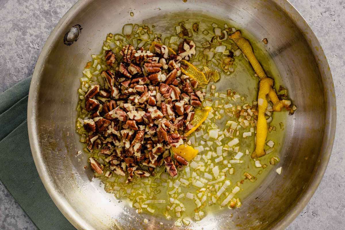 chopped pecans in a skillet with oil and lemon peels