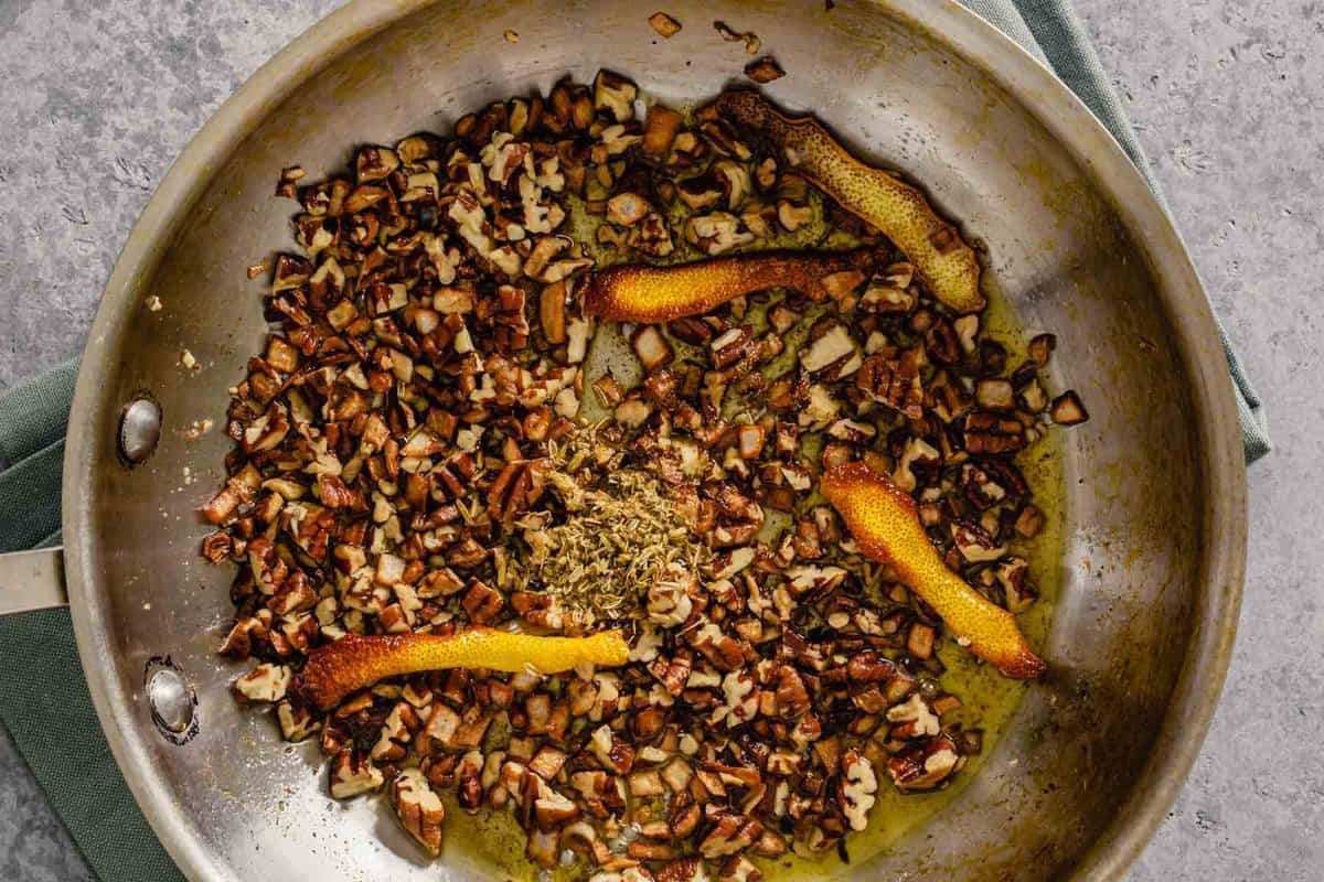 toasted nuts and spices in a skillet with oil and lemon peels