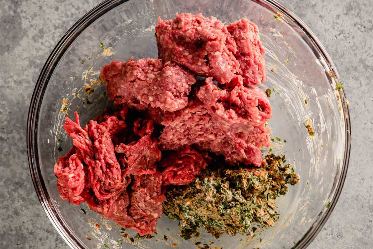 ground beef and ground lamb in a bowl with herbs mixed with yogurt
