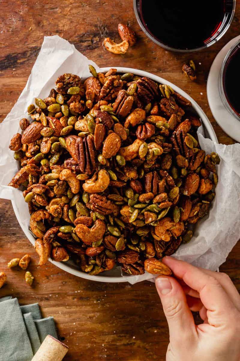 spiced nuts in a white bowl set on a wood table