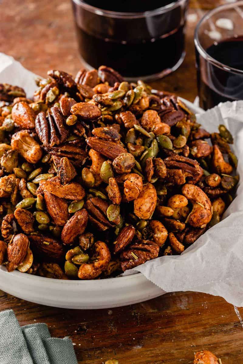 spiced nuts in a white bowl set on a wood table