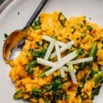 Close up photo of carrot risotto with peas and asparagus