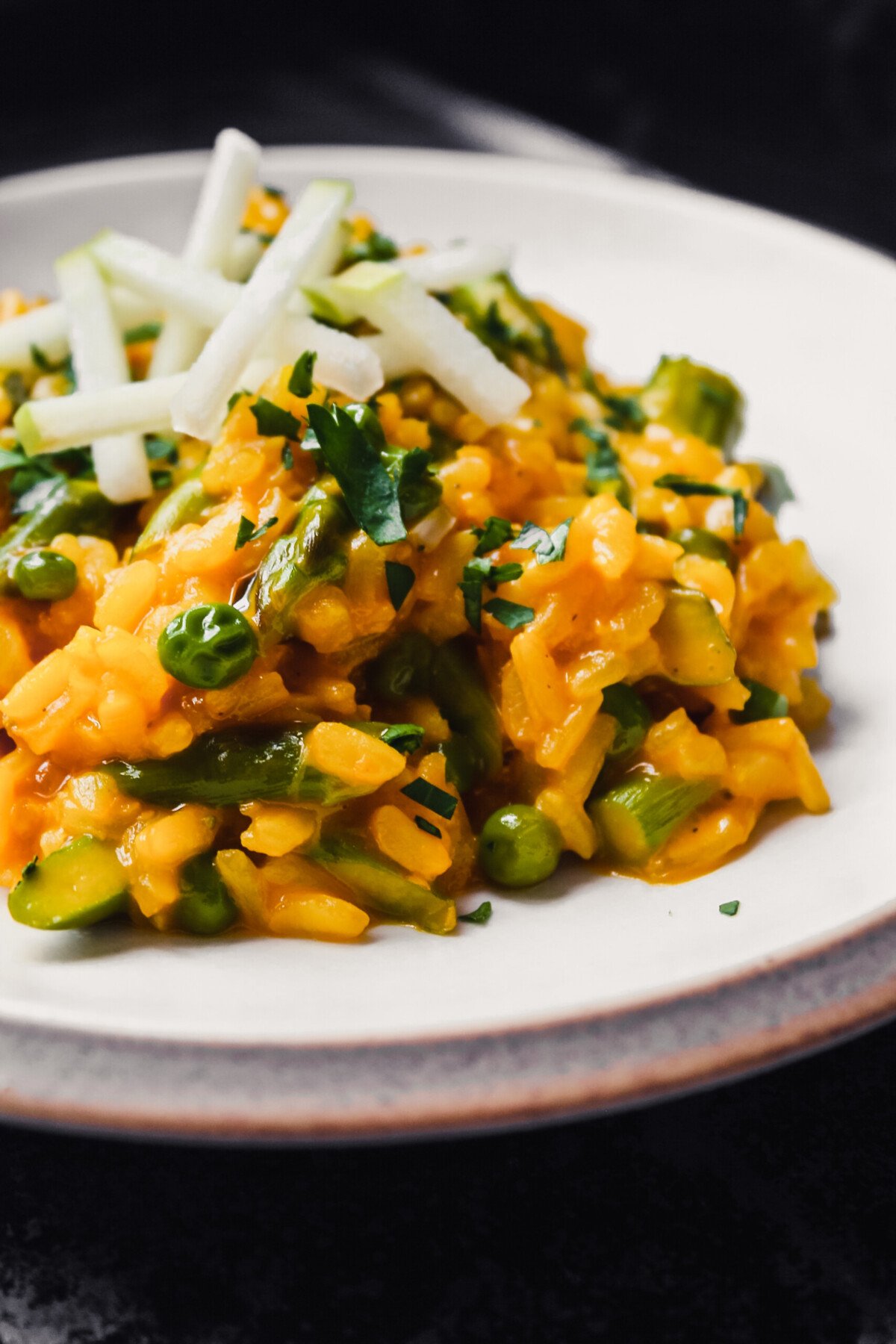 Close up photo of carrot risotto with peas and asparagus
