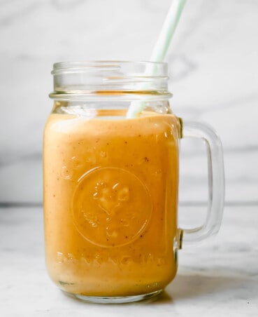 Photograph of ball glass filled with an orange-colored carrot smoothie