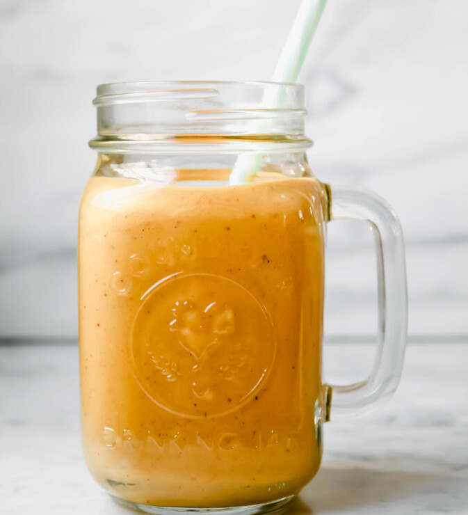 Photograph of ball glass filled with an orange-colored carrot smoothie