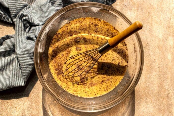 spiced custard in a glass bowl with a whisk in it