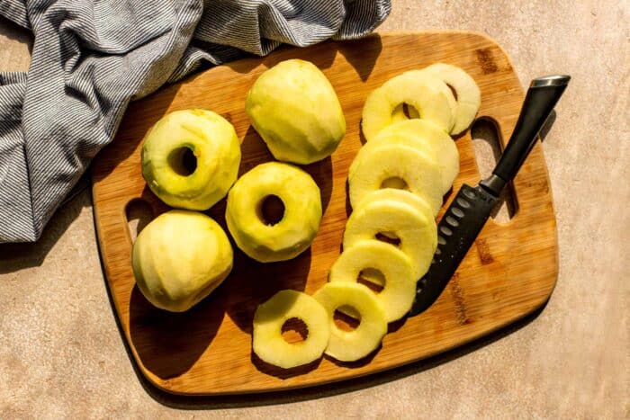 peeled, cored and sliced apples on a wooden cutting board