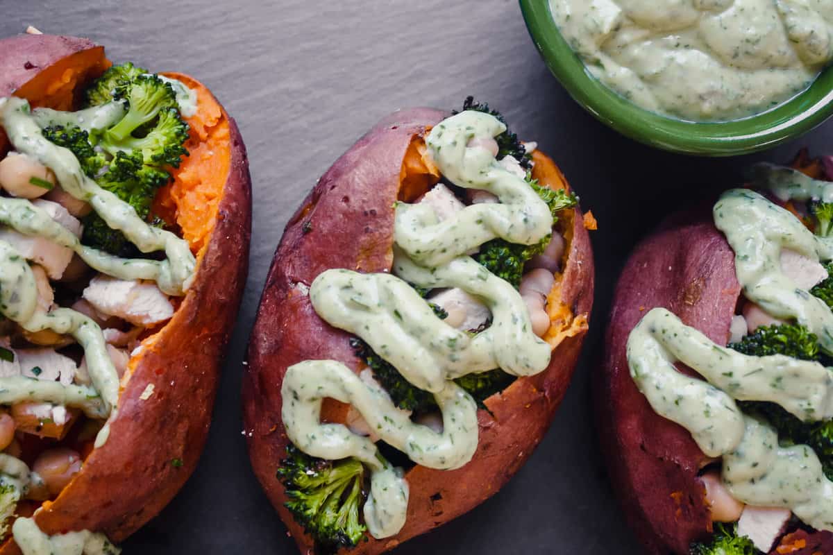 Overhead photograph of stuffed sweet potatoes drizzled with a green goddess dressing