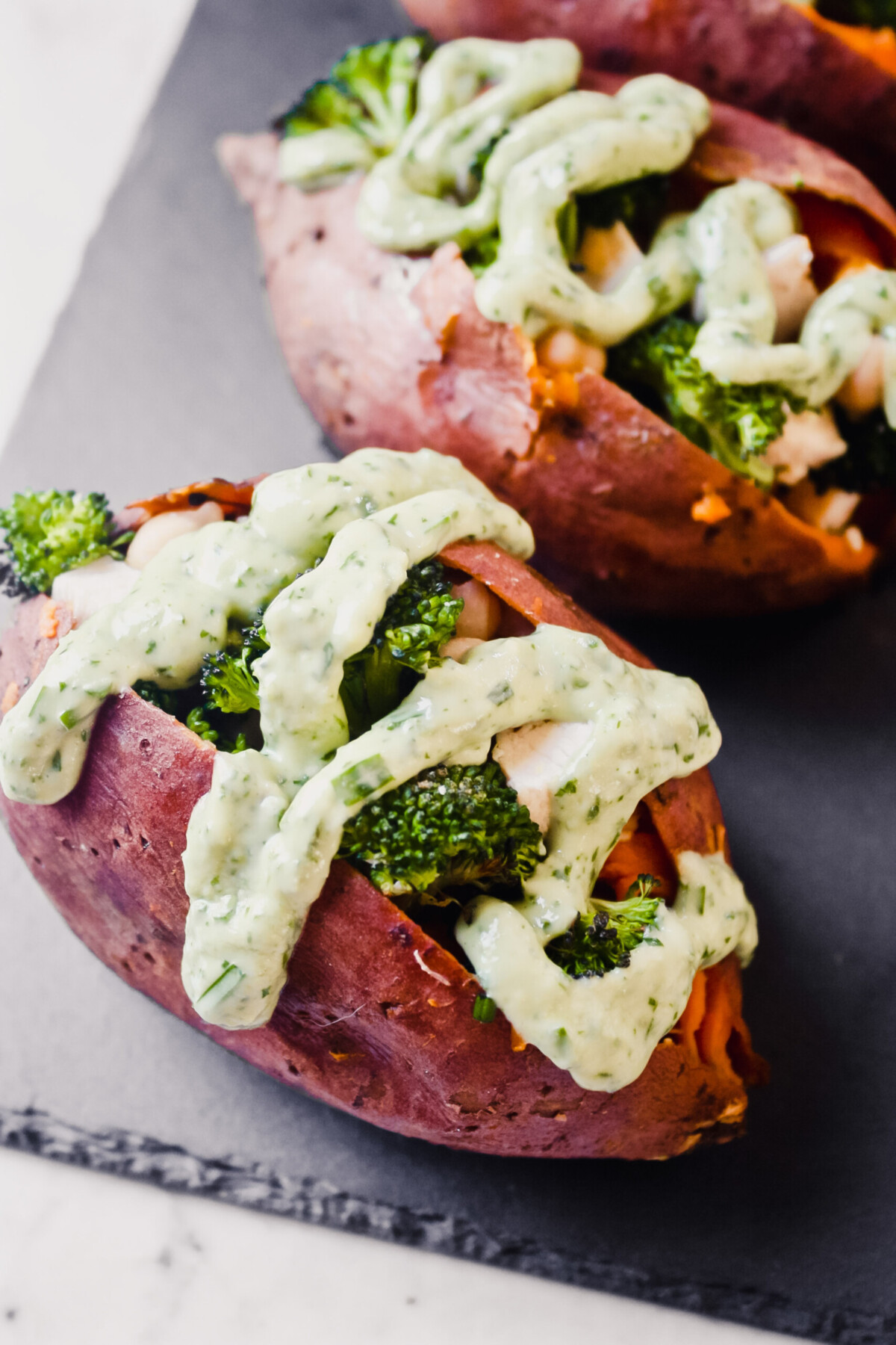  photograph of stuffed sweet potatoes drizzled with a green goddess dressing