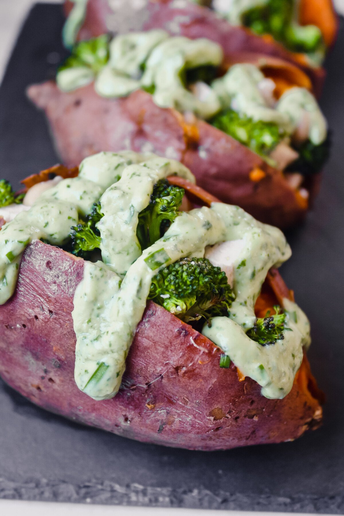 Overhead photograph of stuffed sweet potatoes drizzled with a green goddess dressing