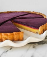 Tart slices, with yellow and purple layers, set on top of a marble surface.