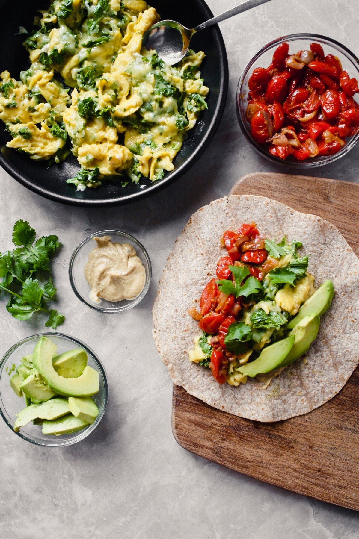 overhead photograph of preparation of vegetarian breakfast burritos on a butting board.
