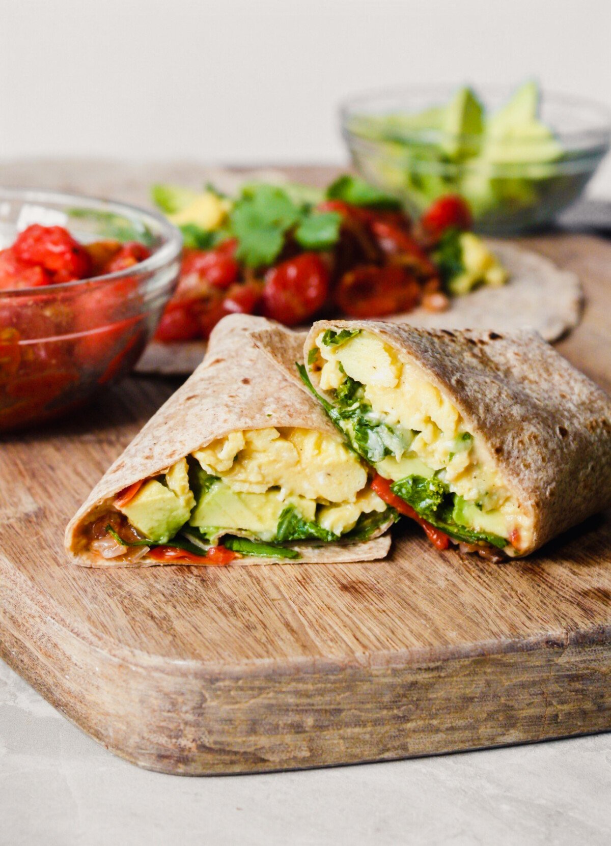Photograph of a breakfast burrito on a wood cutting board
