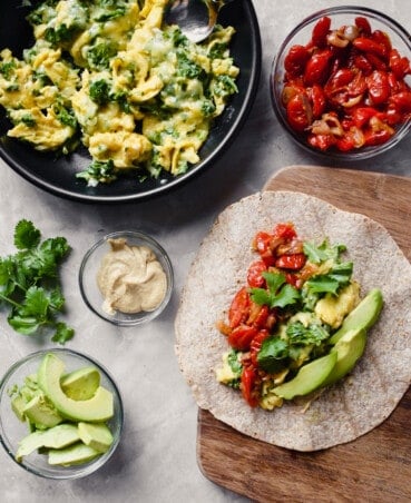 overhead photograph of preparation of vegetarian breakfast burritos on a butting board.
