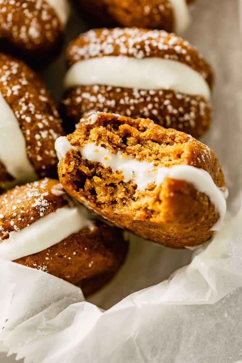 pumpkin whoopie pies arranged in a bowl lined with parchment paper