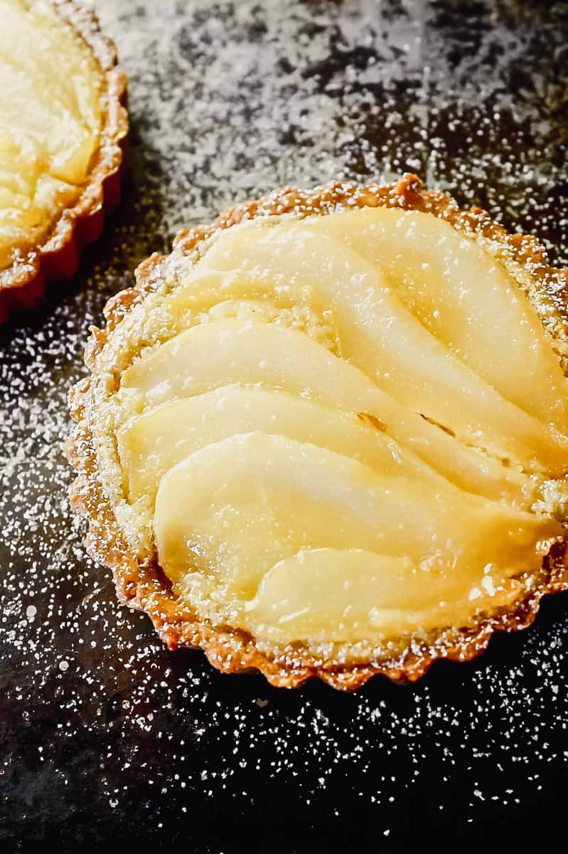 Overhead image of a mini tart on a balking sheet topped with layered of poaches pears