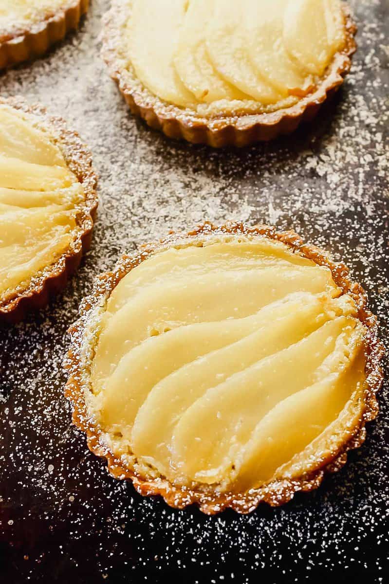 Overhead image of a mini tart on a balking sheet topped with layered of poaches pears