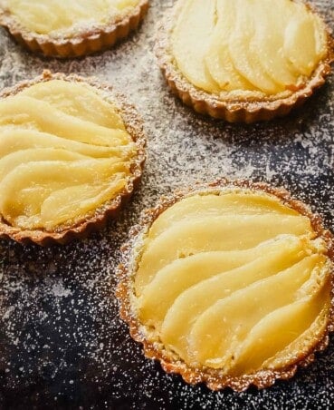 Overhead image of a mini tarts on a balking sheet topped with layered of poaches pears