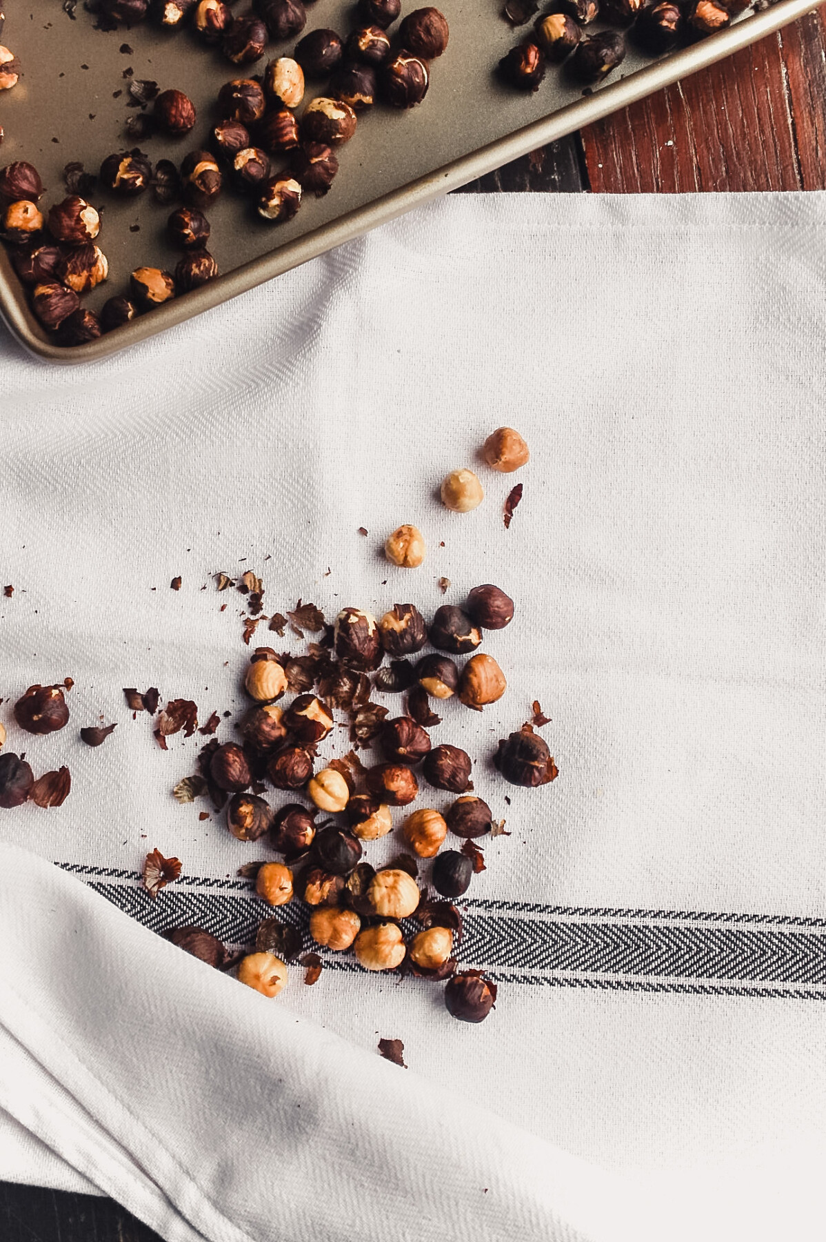 Photograph of toasted hazelnuts laying on a white kitchen towel