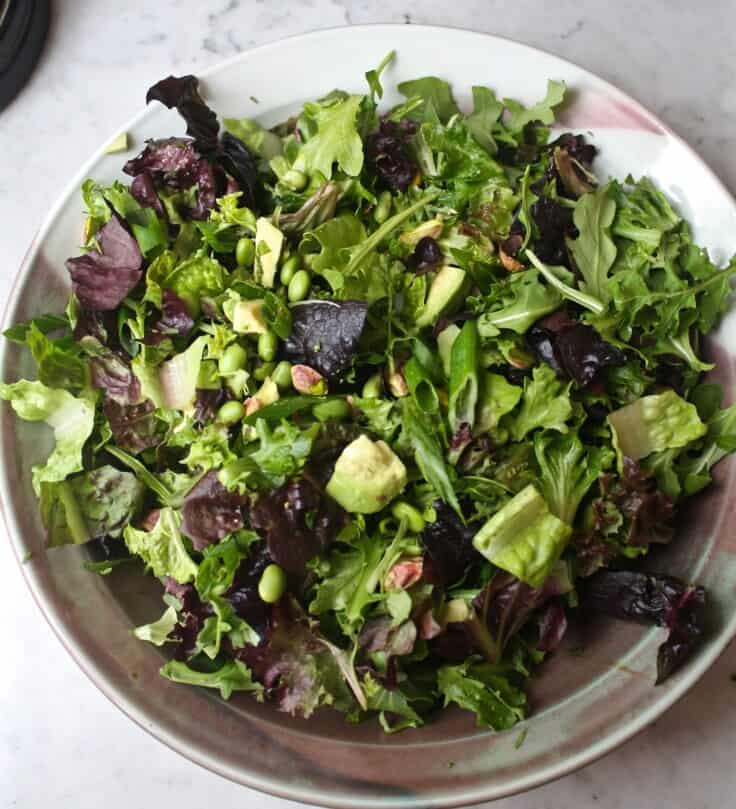 Large green salad in a bowl set on a marble table