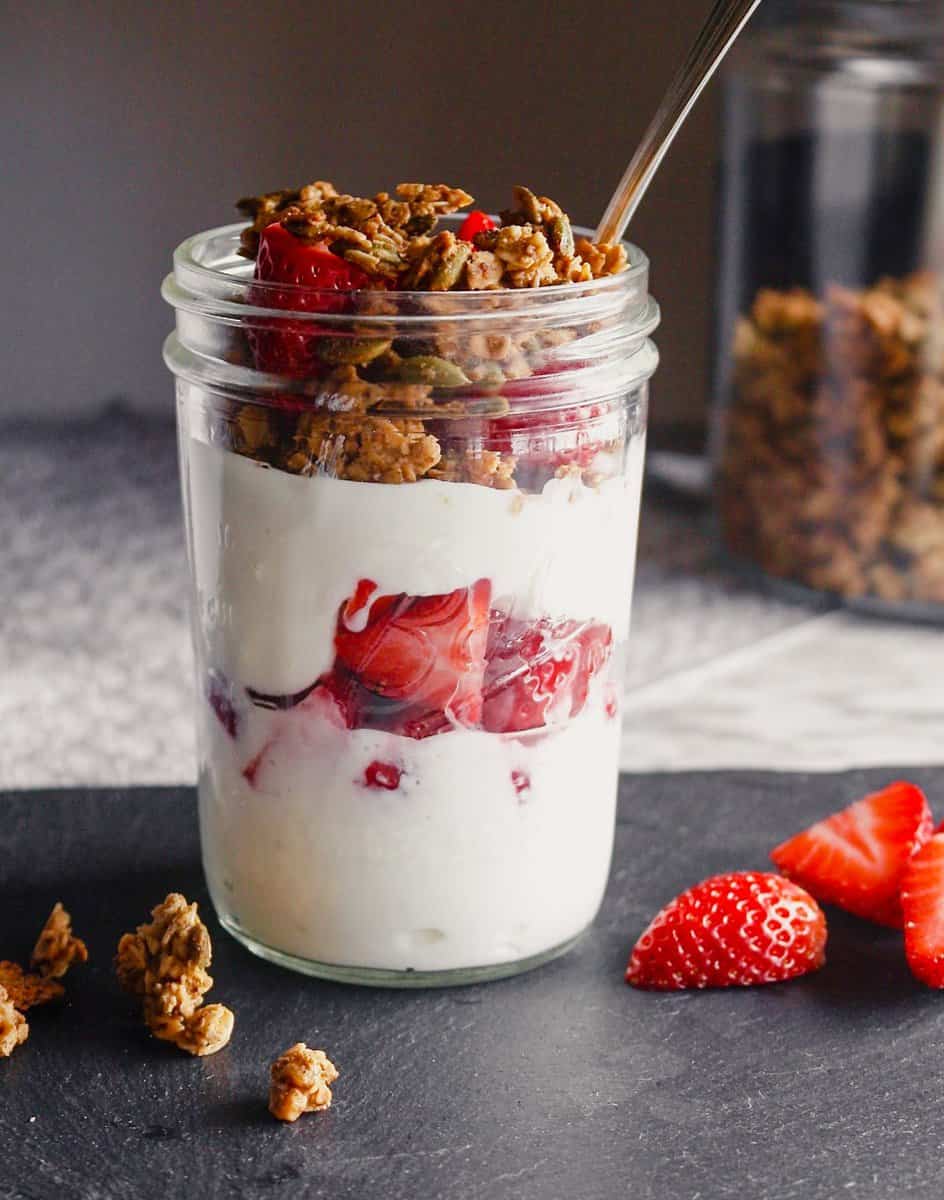 Photograph of a strawberry yogurt parfait with granola layered in a Ball jar