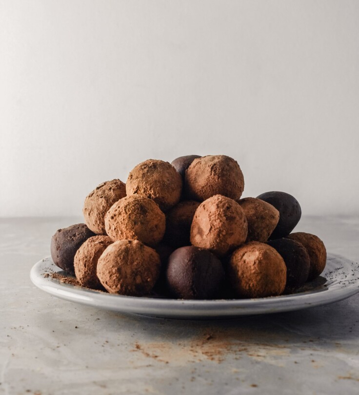 Photograph of dark chocolate truffles stacked on top of a gray plate