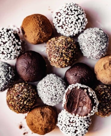 dark chocolate truffles coated in cocoa, sprinkles and sugar arranged on a round pink plate