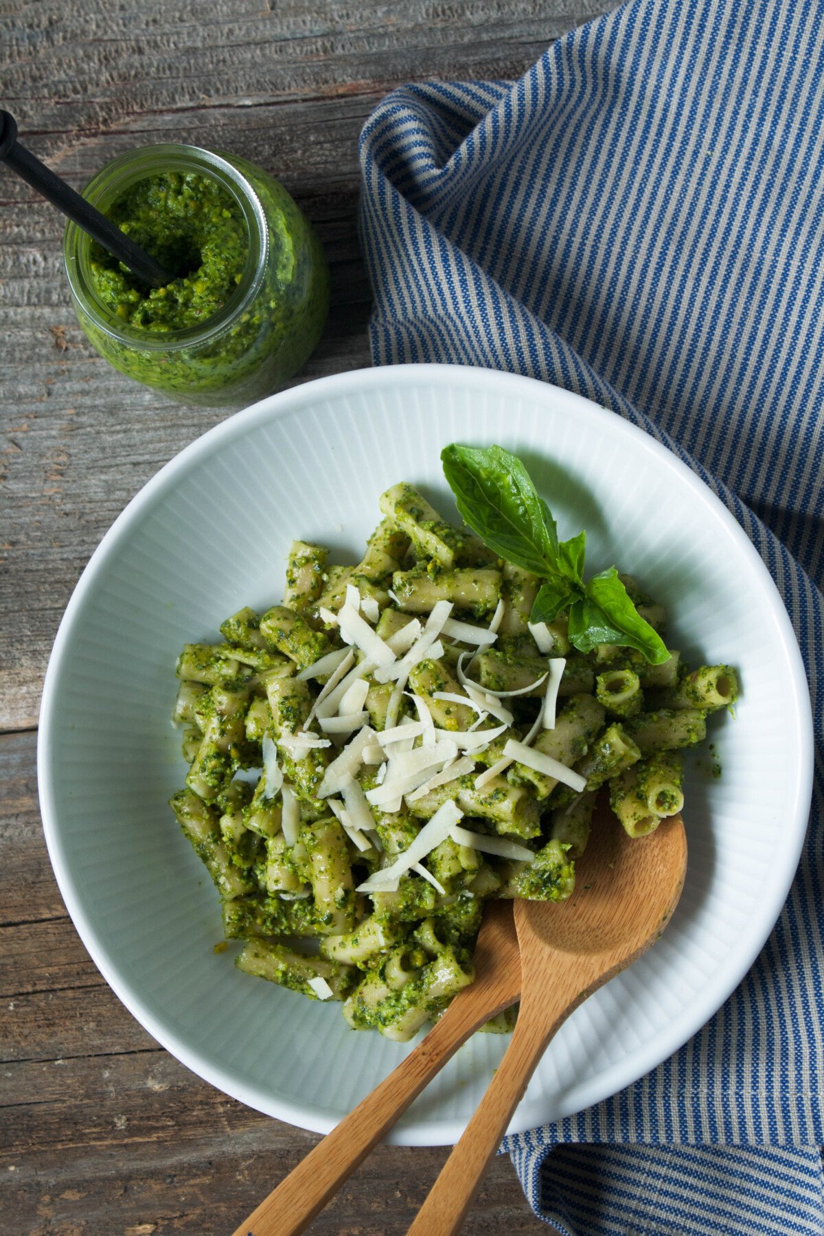 Photo of pesto pasta in a white bowl on a wood table