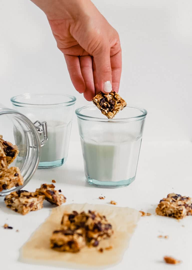 Granola bite being dunked in a glass of milk 
