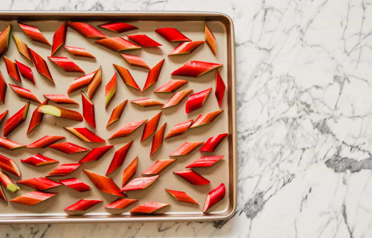 Photograph of rhubarb pieces scattered on a sheet pan.