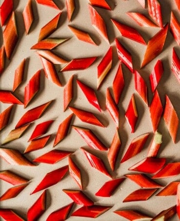 Photograph of rhubarb pieces scattered on a sheet pan.