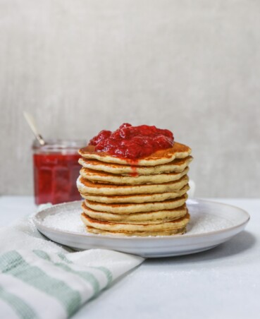Toasted Oat Pancakes stacked on a white plate topped with a Quick Berry Compote