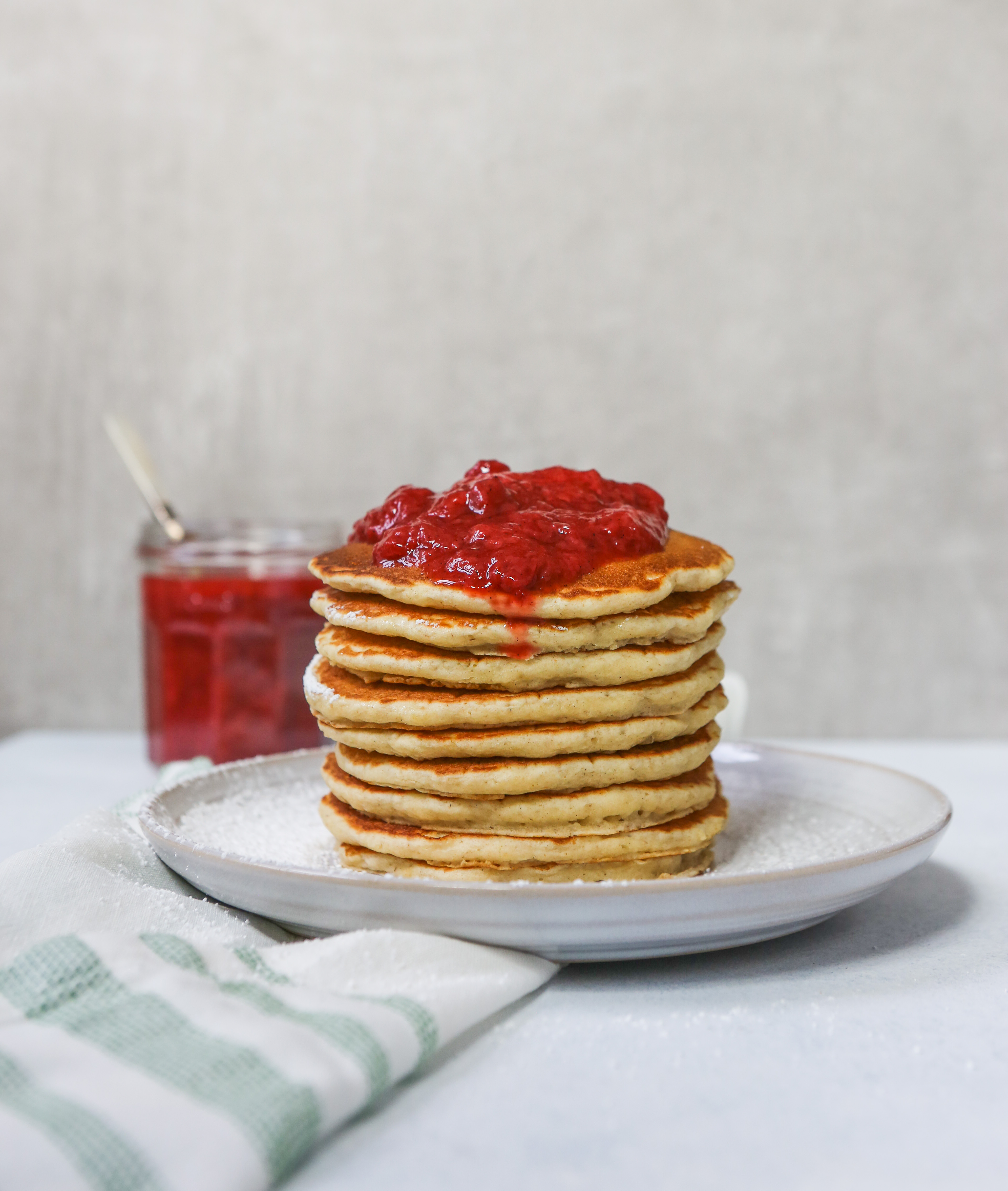 Toasted Oat Pancakes stacked on a white plate topped with a Quick Berry Compote
