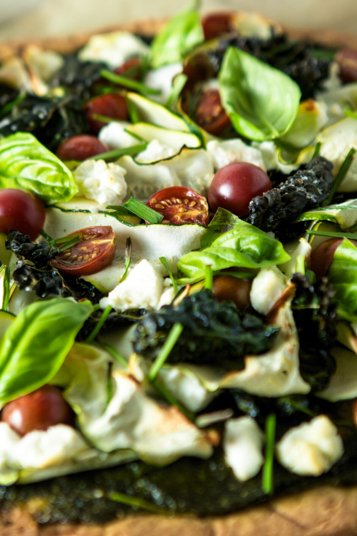 close up photograph of pizza toppings including basil, tomatoes and kale