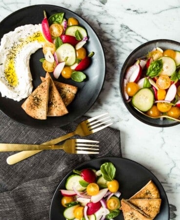 image of vegetables and labneh on a black plate with pita wedges