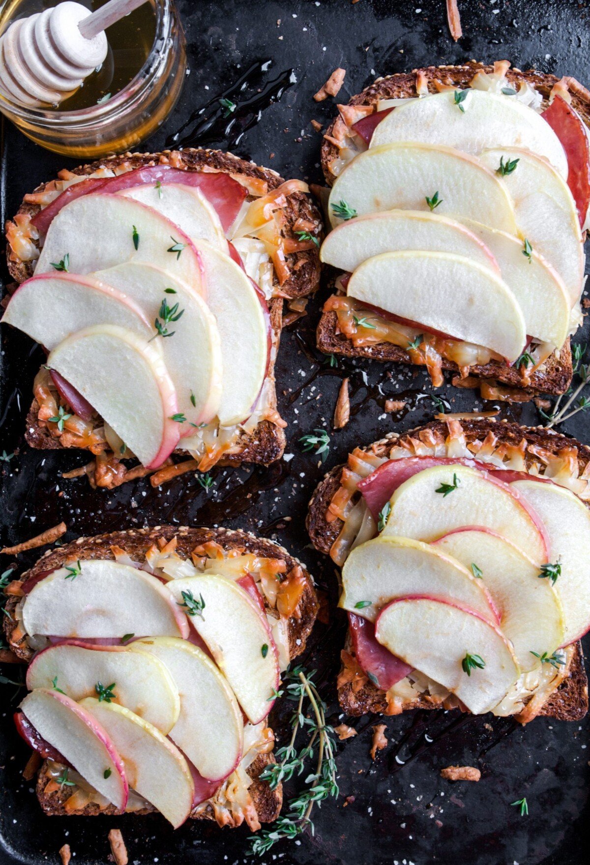 Toasted whole grain bread gets topped with creamy smoked gruyere, salty ham, and slices of honeycrisp apple. It gets broiled to melty perfection then drizzled with honey and earthy thyme, these toasts are perfect for breakfast, lunch, or dinner. | Zestful Kitchen