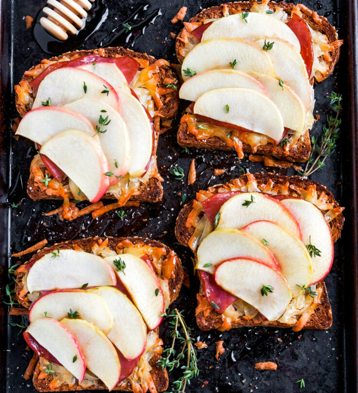 Open faced sandwiches with melted cheese and apple on baking sheet