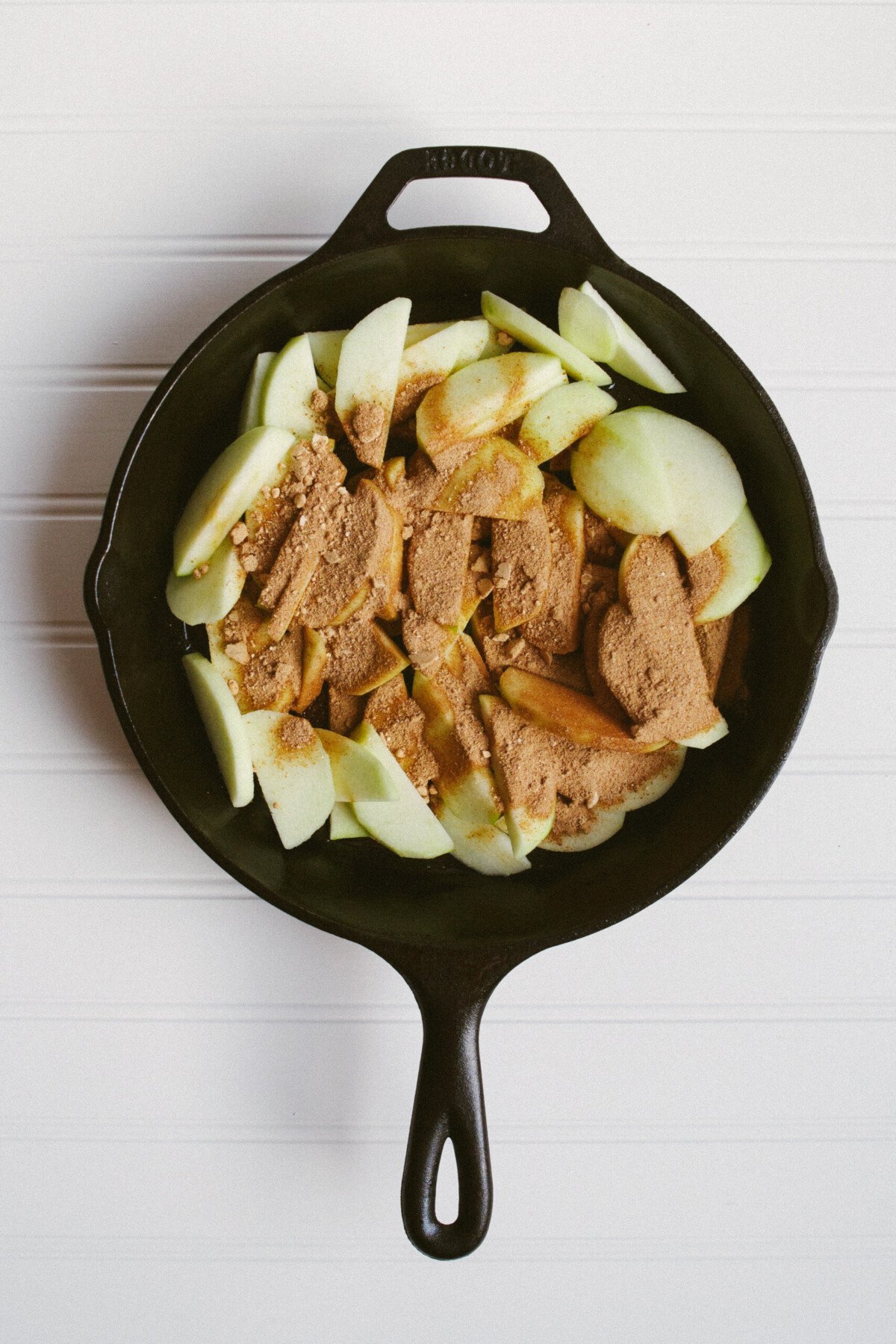 Photo of sliced apples and coconut sugar in a cast iron skillet