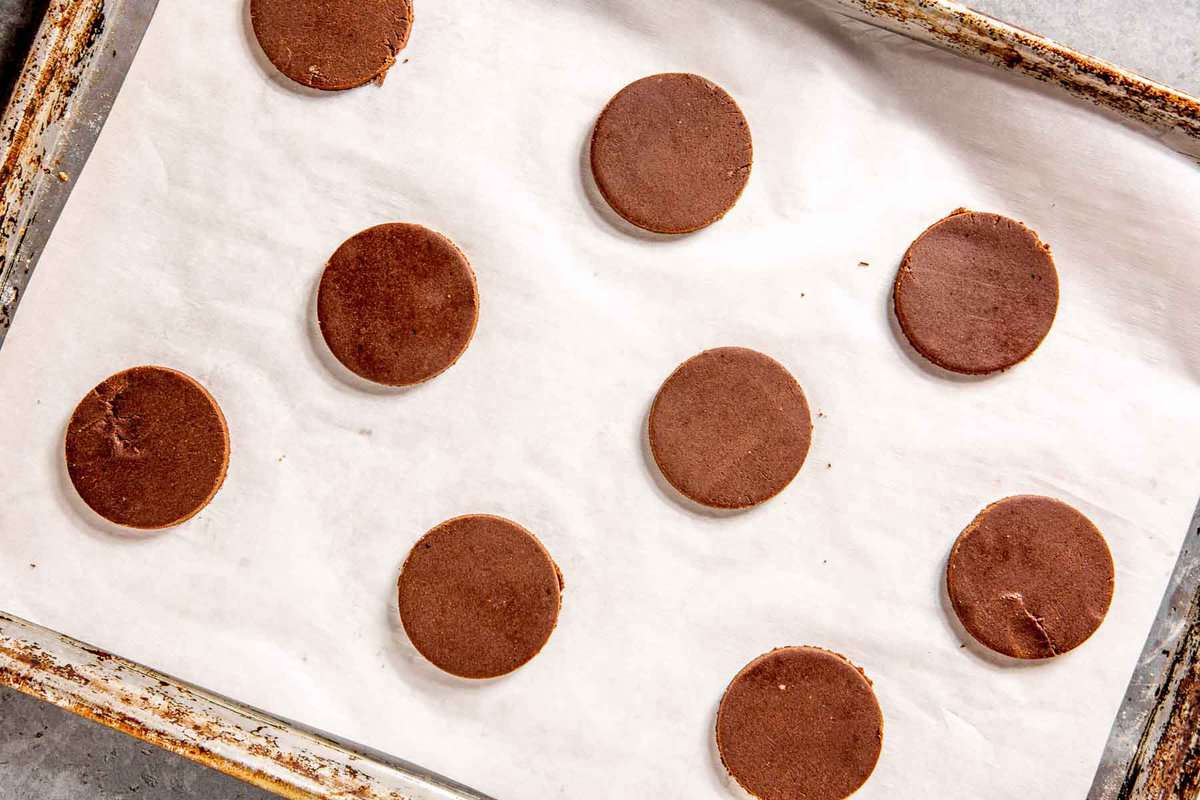 chocolate cookie dough disks on a parchment-lined baking sheet