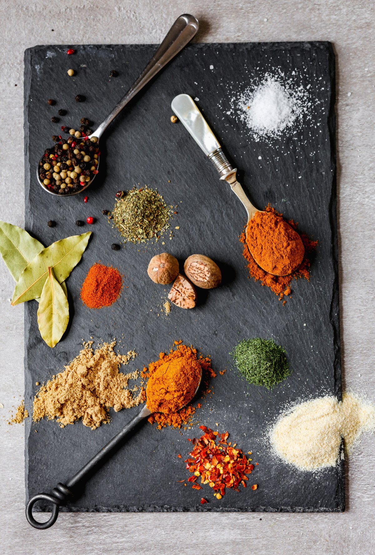 vibrant piles of colorful spices arranges on a black slate plate.