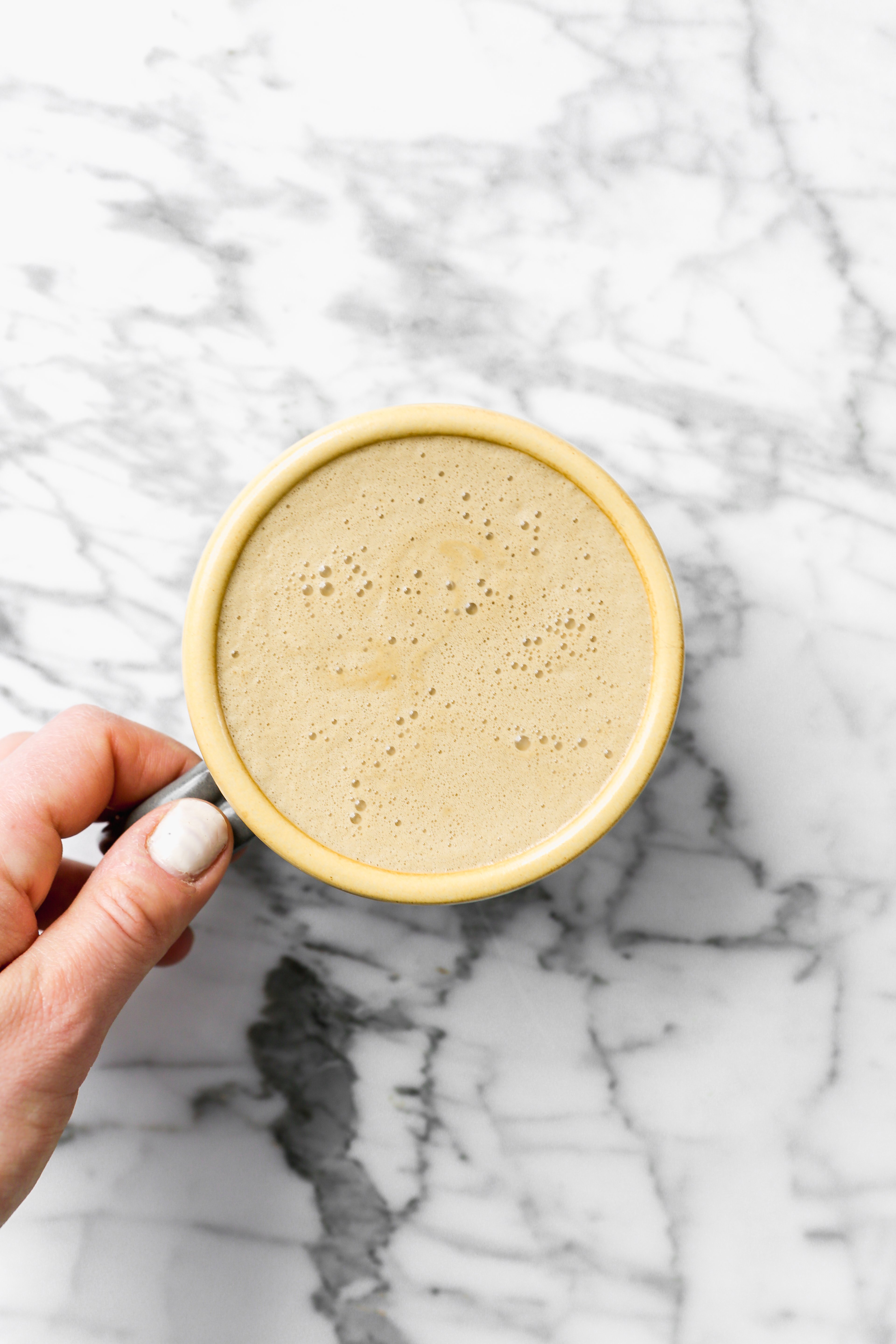 Latte in a mug set on a white marble background