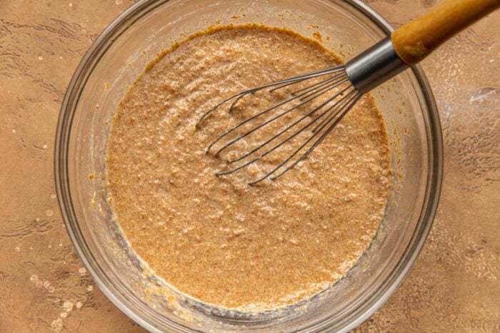 bran muffin batter in a glass mixing bowl with a whisk set in it
