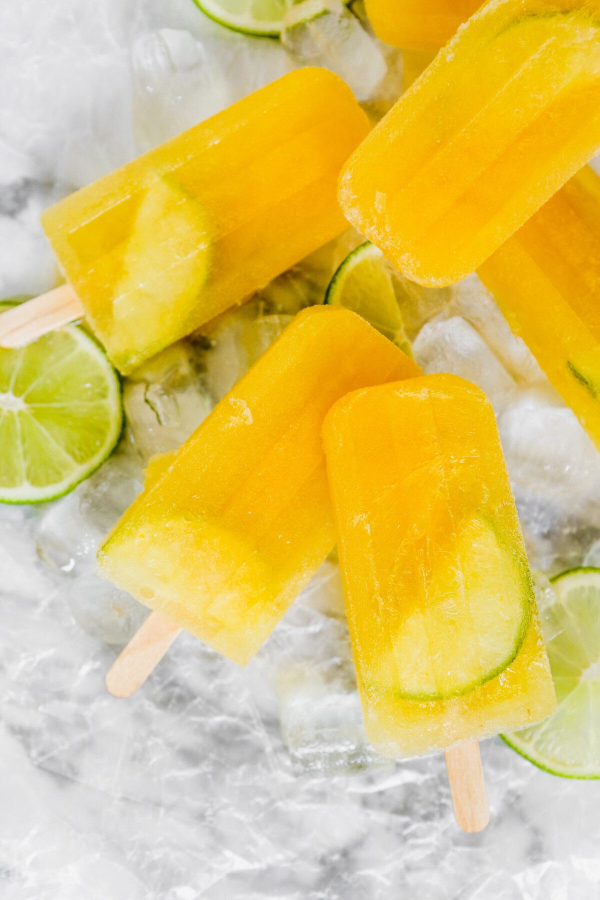bright yellow popsicles set on a white marble surface