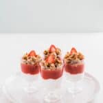 Yogurt and fruit parfaits with granola and strawberries set on a white plate