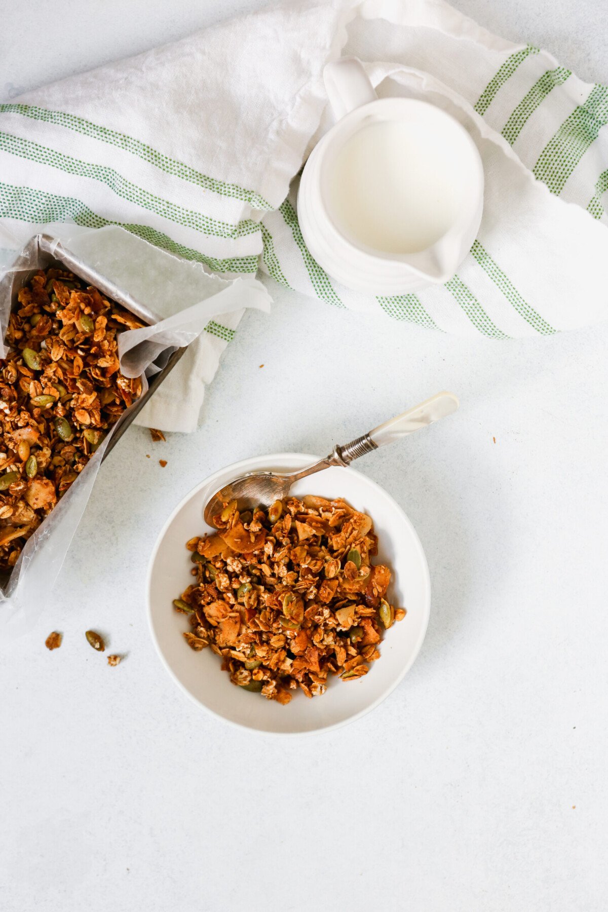 Homemade healthy granola recipe in a white bowl and in a metal tin
