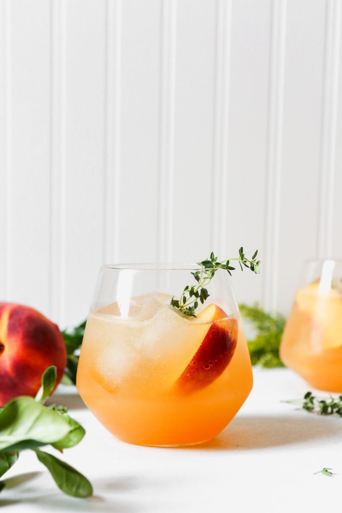 Peach and thyme cocktails set on a marble surface